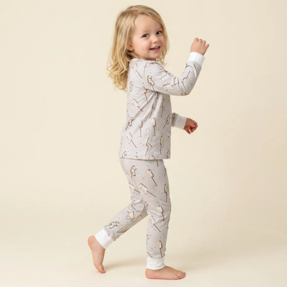 Peuter loopt in cream pyjama met hobbelpaard-print